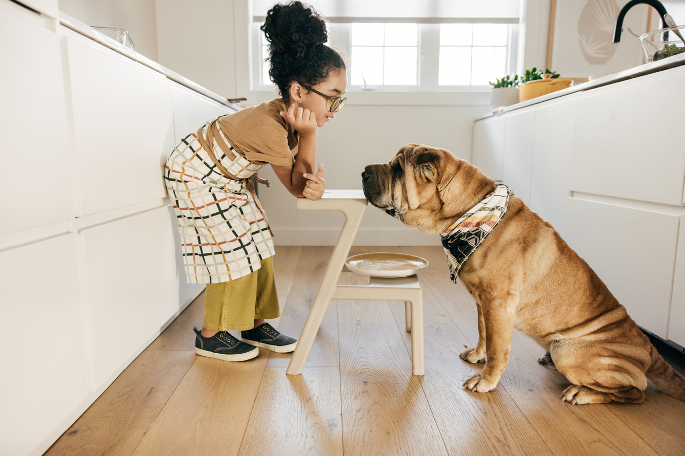 Girl talking to her dog in the kitchen.
