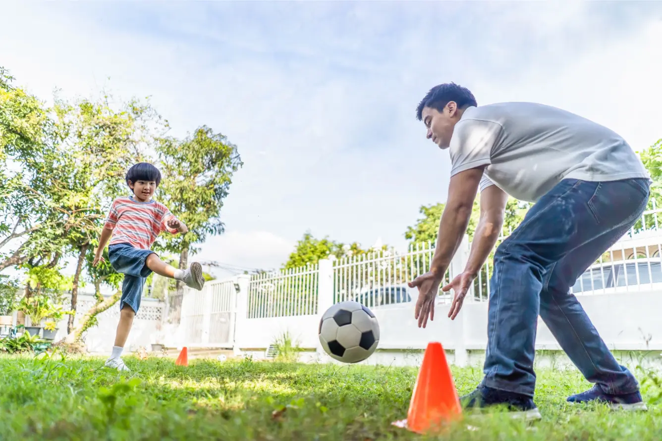 Family playing soccer in their yard.