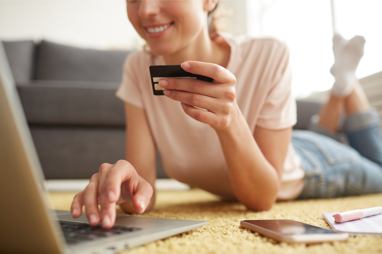 Woman smiling and doing online banking with her client card in hand