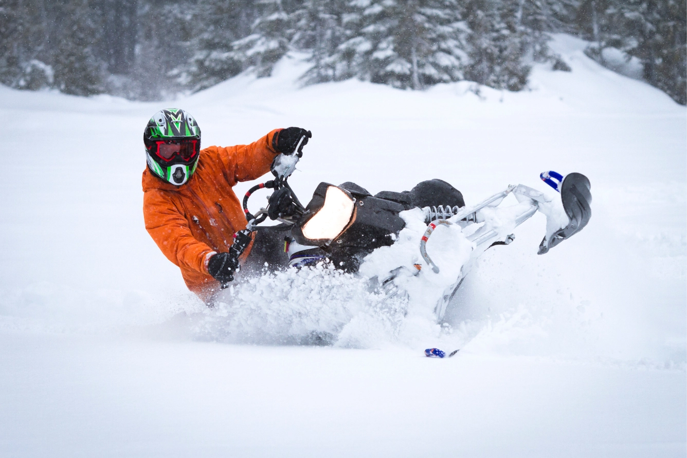 Individual slides across the snow on their snowmobile.
