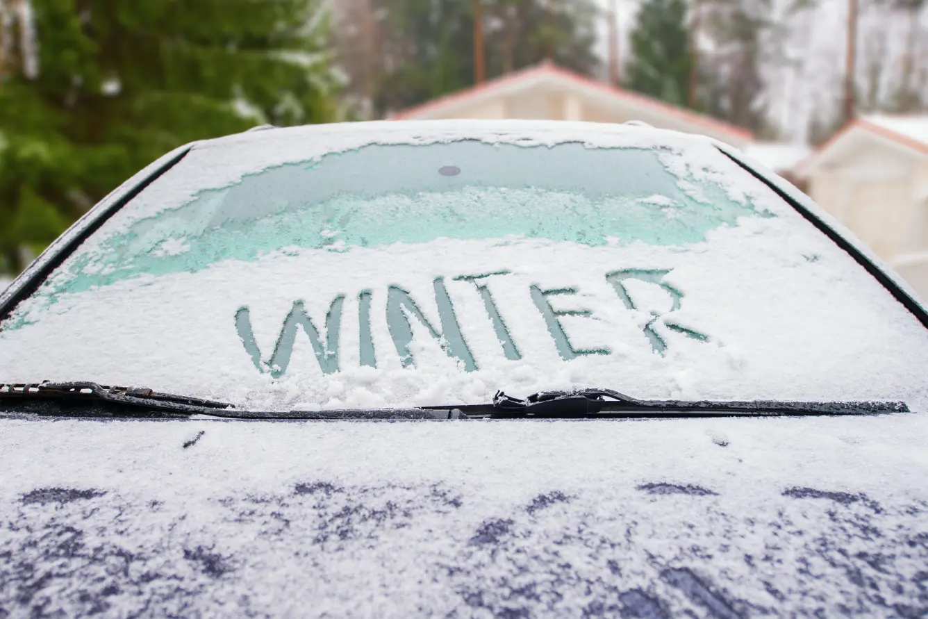 Parked car with WINTER written into the snow on the windshield.