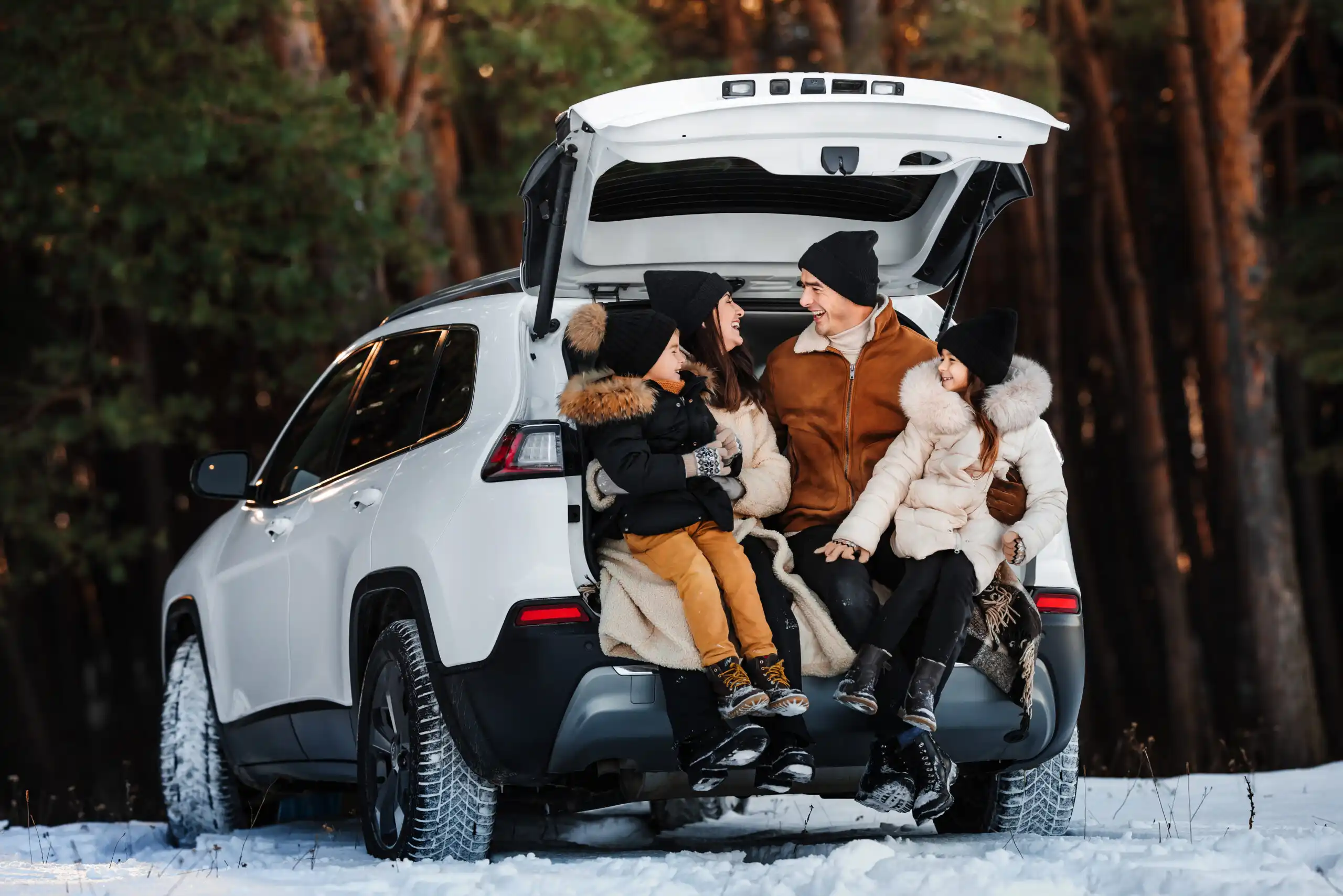 A family enjoying a cozy winter moment at the back of their car—symbolizing the peace of mind that comes from proper car maintenance and the security of reliable auto insurance