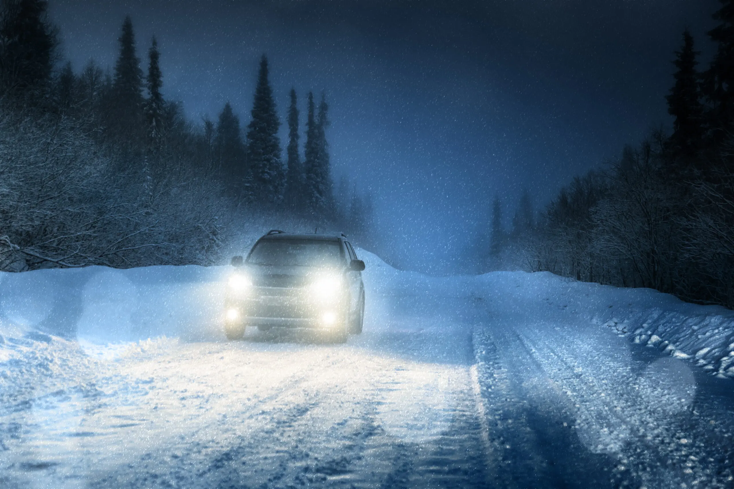 Car driving through a serene winter forest with headlights glowing symbolizing reliability and the peace of mind that comes with trusted auto insurance