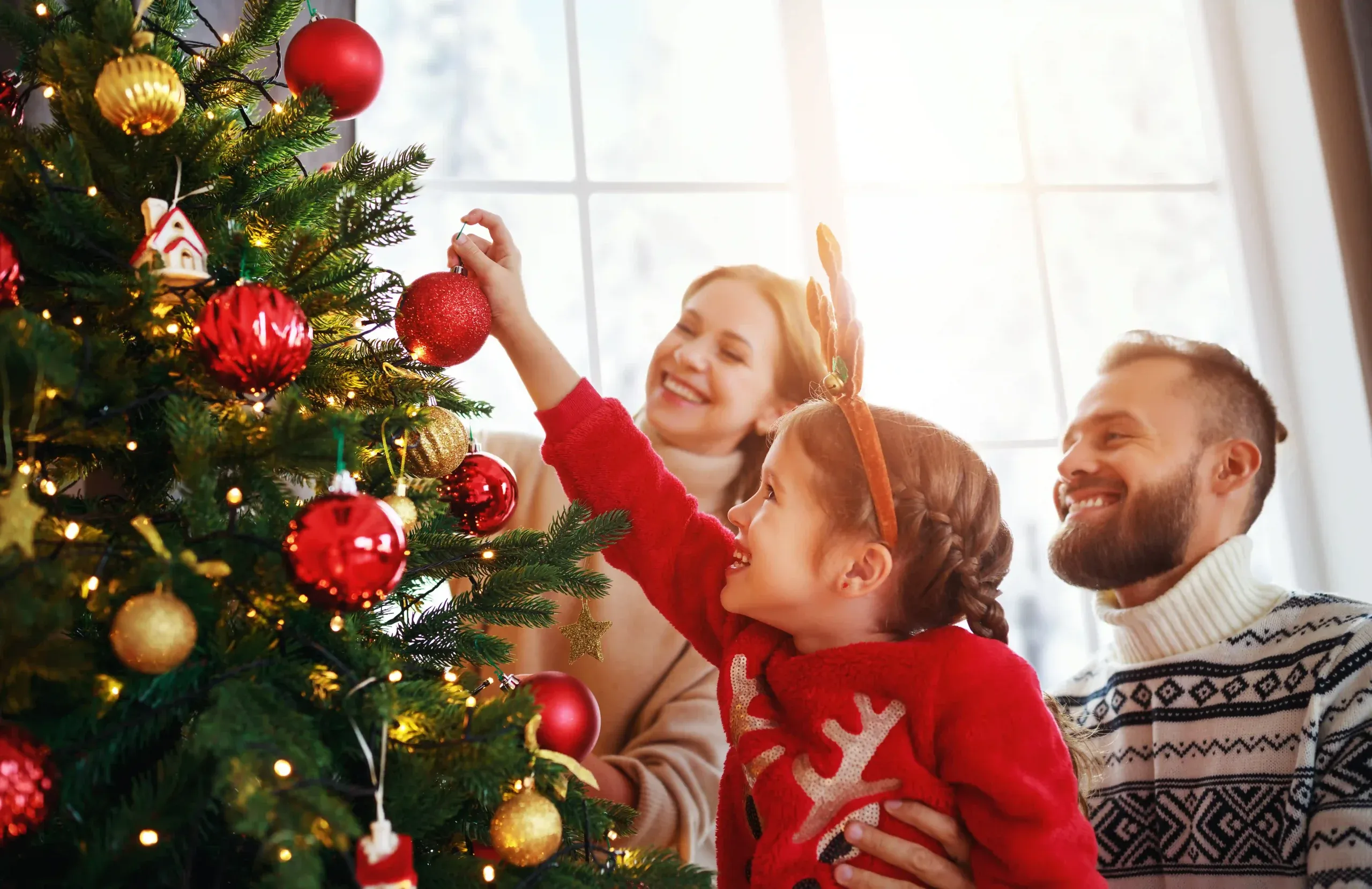 Family decorating a christmas tree together indoors