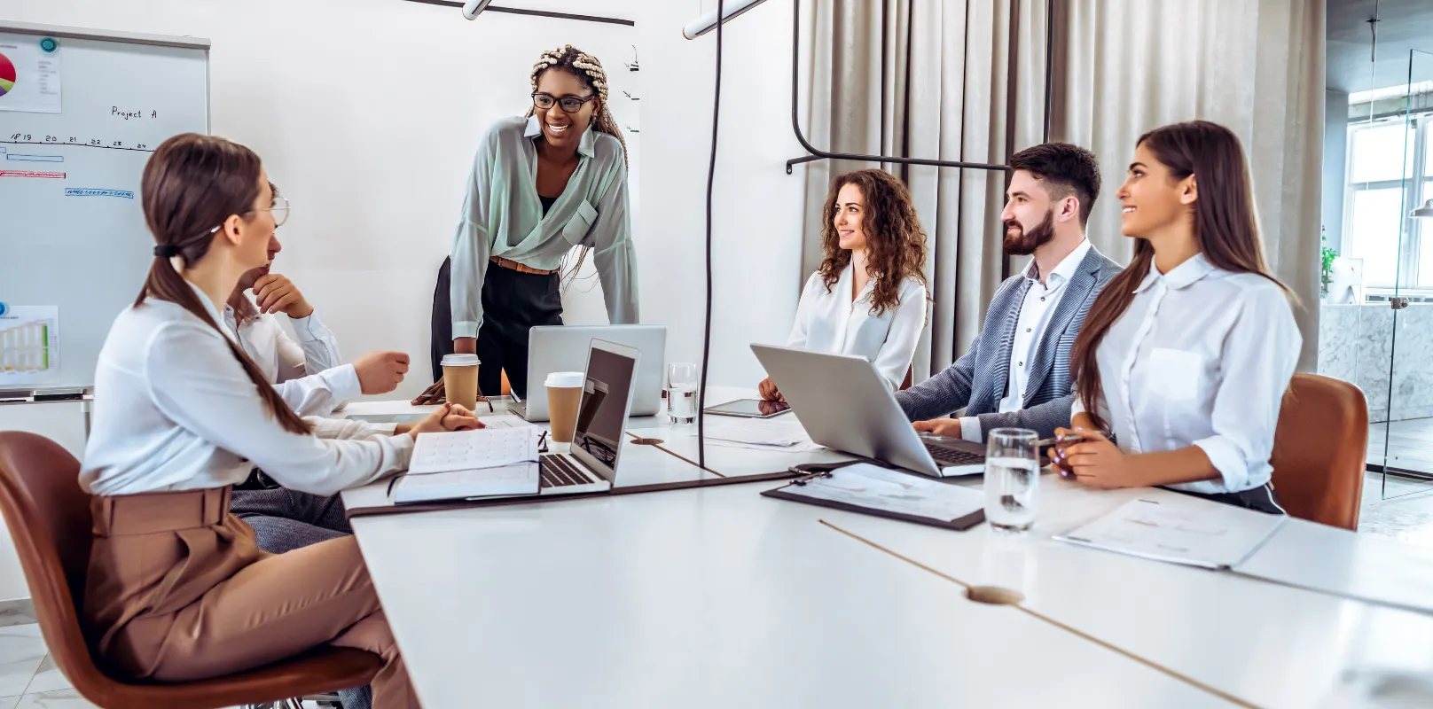 Business team gathered in an office for a meeting, discussing work around a conference table.