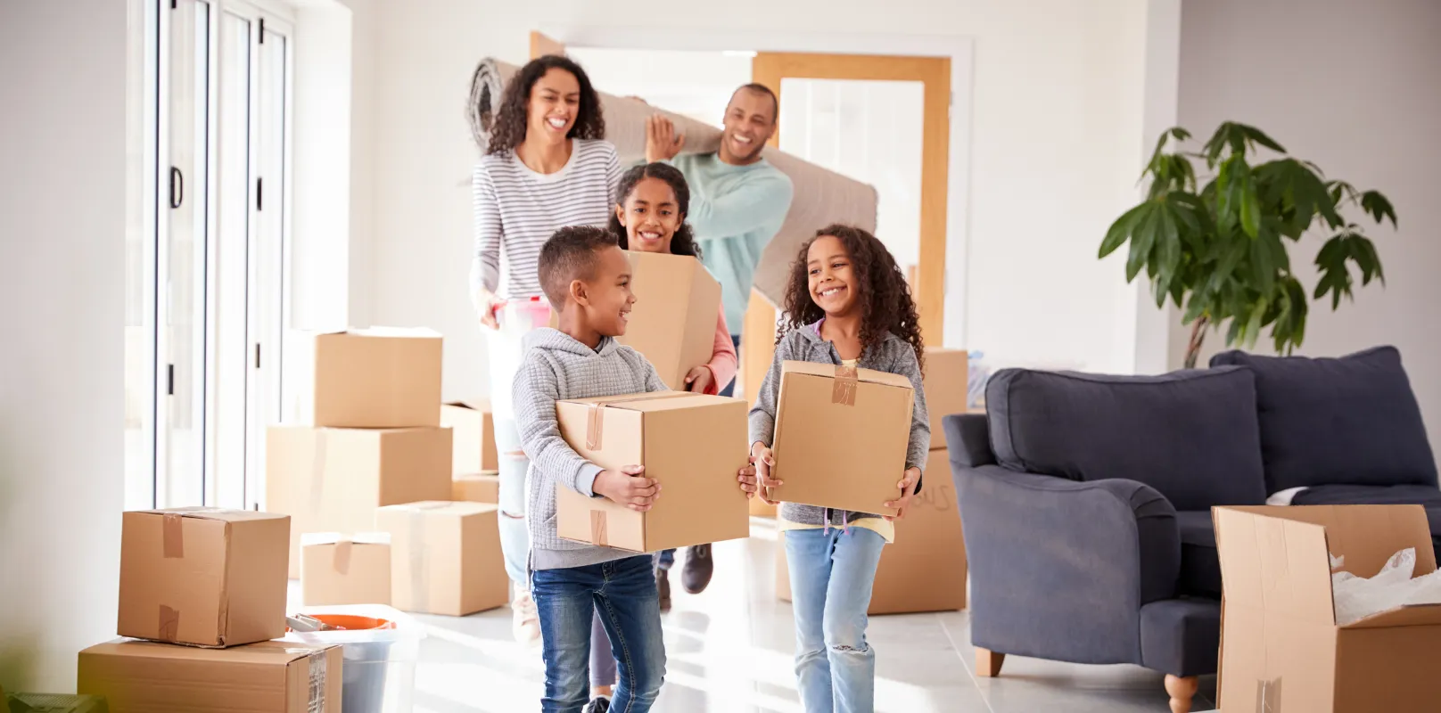 A happy tenant family moving into a rental property while carrying boxes, reflecting a positive move‑in experience and the reassurance provided by rental property insurance.