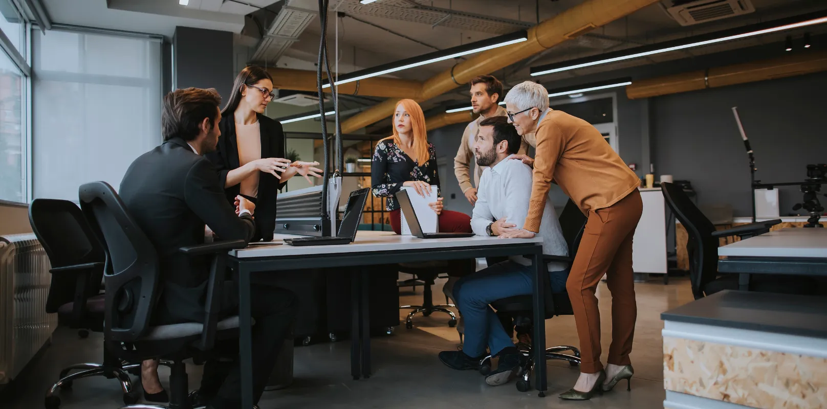 Professionals collaborating in an office setting while reviewing documents related to cybersecurity risk management and cyber liability insurance.