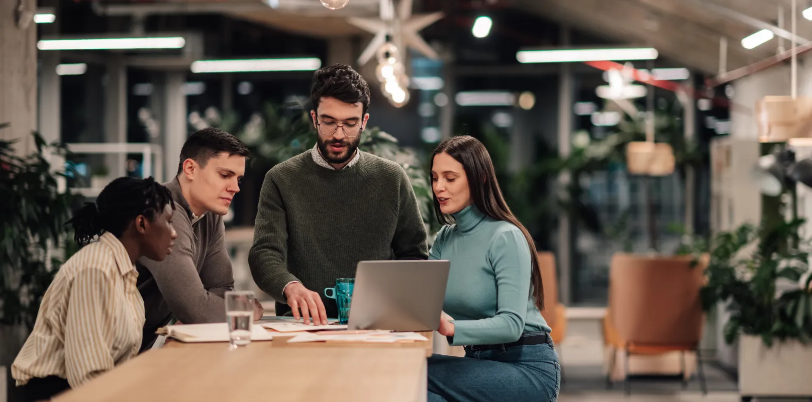 Business team collaborating around a laptop in a modern office, highlighting cybersecurity insurance and cyber risk management for organizations.