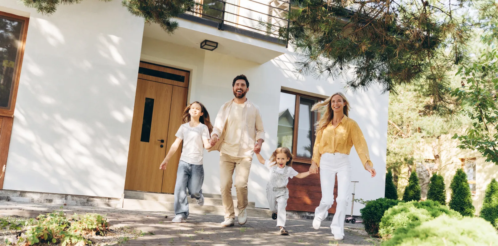 A family standing together while admiring their two‑storey house, representing the peace of mind that comes with reliable home insurance through firstontario insurance brokers.