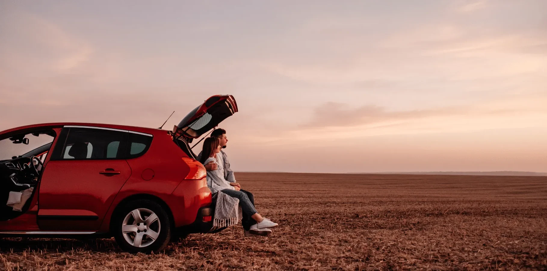 Drivers sitting near the open trunk of a car during a trip, representing vehicle protection through ontario auto insurance coverage.