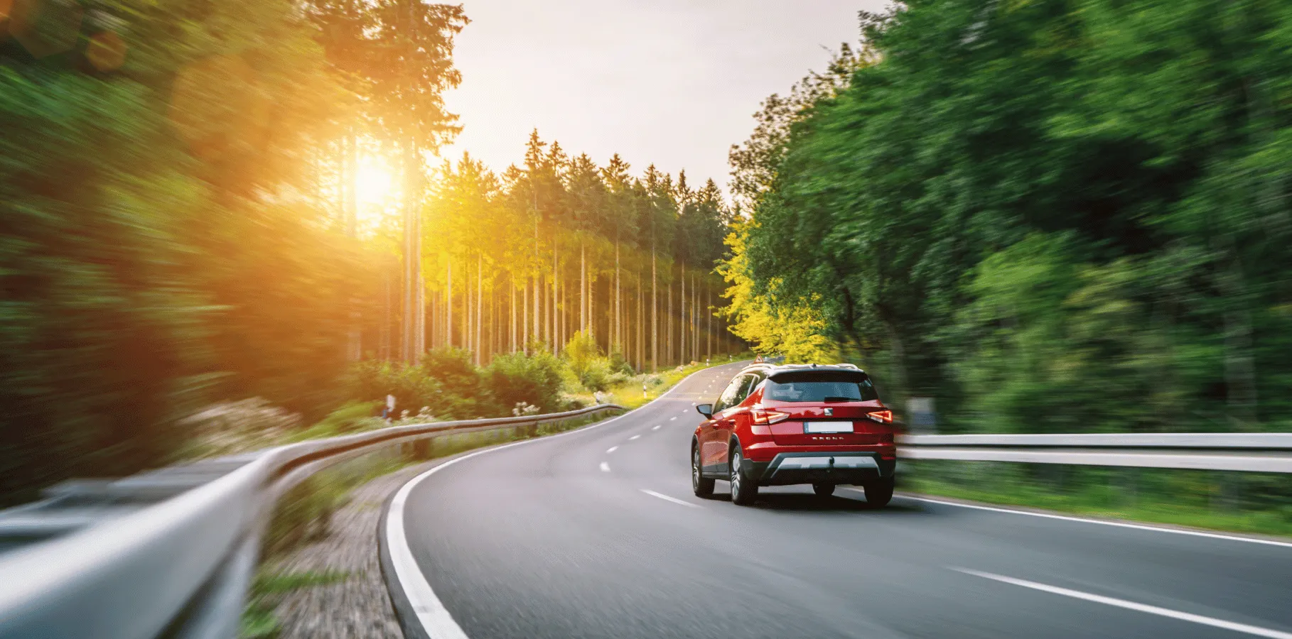 Suv driving on a winding road surrounded by trees, showing typical travel protected by ontario auto insurance.