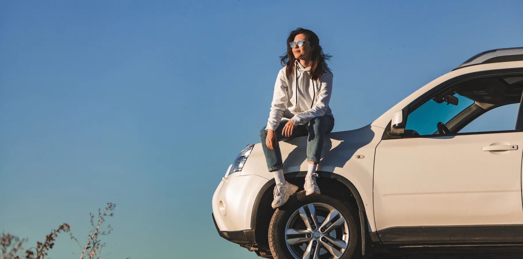 Driver sitting on the front of a parked vehicle outdoors, representing everyday vehicle ownership and auto insurance needs in ontario.